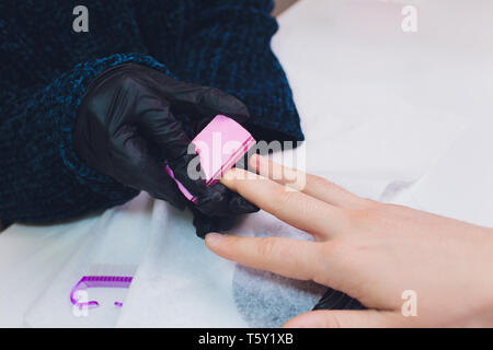 Hände in Handschuhen kümmert sich um Hand Nägel Mann. Maniküre Beauty Salon. Stockfoto
