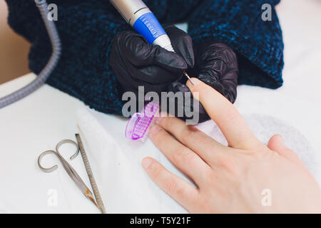 Hände in Handschuhen kümmert sich um Hand Nägel Mann. Maniküre Beauty Salon. Stockfoto