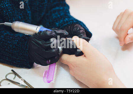 Hände in Handschuhen kümmert sich um Hand Nägel Mann. Maniküre Beauty Salon. Stockfoto