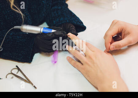 Hände in Handschuhen kümmert sich um Hand Nägel Mann. Maniküre Beauty Salon. Stockfoto