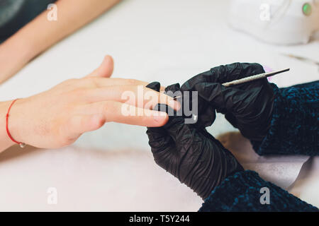 Hände in Handschuhen kümmert sich um Hand Nägel Mann. Maniküre Beauty Salon. Stockfoto