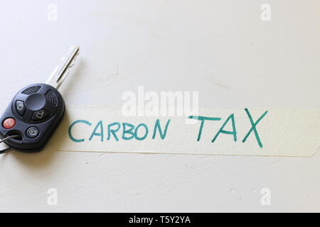 Ein Auto neben eine Notiz, die besagt, dass CO2-Steuer. Konzept der steigenden Kosten zu fahren oder die Probleme mit einer CO2-Steuer. Stockfoto