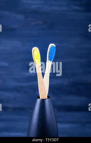 Leuchtend gelb und blau Bambus Zahnbürsten auf dem dunkelblauen Hintergrund. Umweltfreundliches Konzept. Minimalismus Kopie Raum Stockfoto