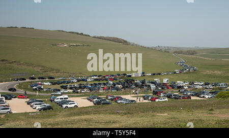 Fahrzeuge auf einem überfüllten Parkplatz und entlang der Straße, die zu einem beliebten Reiseziel an der South Downs Way East Sussex in der Nähe von Beachy Head geparkt Stockfoto