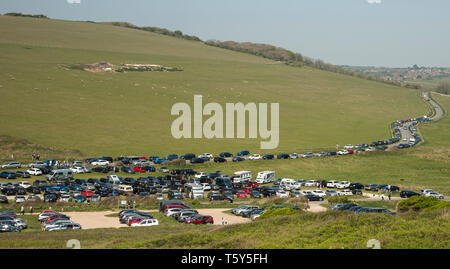 Fahrzeuge auf einem überfüllten Parkplatz und entlang der Straße, die zu einem beliebten Reiseziel an der South Downs Way East Sussex in der Nähe von Beachy Head geparkt Stockfoto