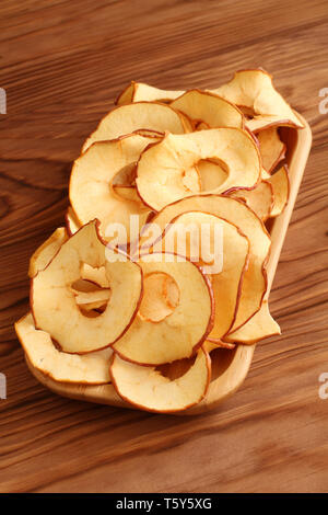 Apple Chips liegen auf einem Bambus Platte auf einem Holztisch. Nahaufnahme. Makro Stockfoto