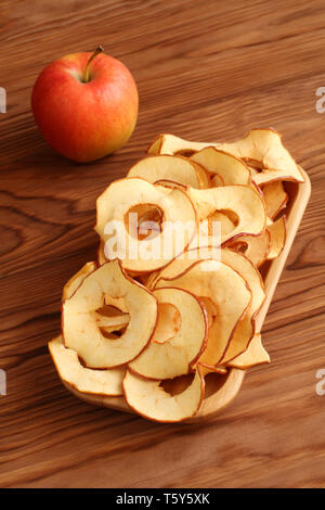 Apple Chips liegen auf einem Bambus Platte auf einem Holztisch. Nahaufnahme. Makro Stockfoto