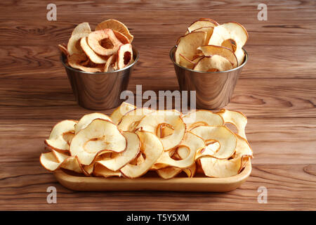 Apple Chips liegen auf einem Bambus Platte auf einem Holztisch. Nahaufnahme. Makro Stockfoto