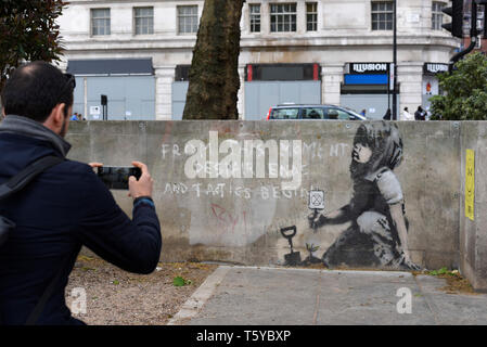 London, Großbritannien. 27. April 2019. Ein Mann Ansichten ein Kunstwerk, das an einer Wand im Marble Arch nach zehn Tagen der Proteste in London vom Aussterben Rebellion, eine Gruppe fordert, dass Regierungen Maßnahmen zur Bekämpfung des Klimawandels erschienen ist. Jetzt in einer Schutzhülle aus Kunststoff abgedeckt, das Kunstwerk ist der gefeierte Street Artist Banksy zugeschrieben worden und stellt ein Bild von einer Pflanze und ein Mädchen, dass eine Gartengeräte mit dem Aussterben Rebellion Logo neben dem Text "Von diesem Moment der Verzweiflung enden und Taktik beginnen". Credit: Stephen Chung/Alamy leben Nachrichten Stockfoto