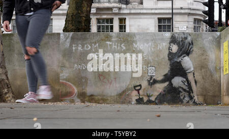 London, Großbritannien. 27. April 2019. Ein Mann durch ein Kunstwerk, das an einer Wand im Marble Arch nach zehn Tagen der Proteste in London vom Aussterben Rebellion, eine Gruppe fordert, dass Regierungen Maßnahmen zur Bekämpfung des Klimawandels erschienen ist. Jetzt in einer Schutzhülle aus Kunststoff abgedeckt, das Kunstwerk ist der gefeierte Street Artist Banksy zugeschrieben worden und stellt ein Bild von einer Pflanze und ein Mädchen, dass eine Gartengeräte mit dem Aussterben Rebellion Logo neben dem Text "Von diesem Moment der Verzweiflung enden und Taktik beginnen". Credit: Stephen Chung/Alamy leben Nachrichten Stockfoto