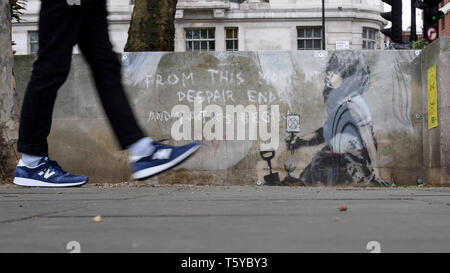 London, Großbritannien. 27. April 2019. Ein Mann durch ein Kunstwerk, das an einer Wand im Marble Arch nach zehn Tagen der Proteste in London vom Aussterben Rebellion, eine Gruppe fordert, dass Regierungen Maßnahmen zur Bekämpfung des Klimawandels erschienen ist. Jetzt in einer Schutzhülle aus Kunststoff abgedeckt, das Kunstwerk ist der gefeierte Street Artist Banksy zugeschrieben worden und stellt ein Bild von einer Pflanze und ein Mädchen, dass eine Gartengeräte mit dem Aussterben Rebellion Logo neben dem Text "Von diesem Moment der Verzweiflung enden und Taktik beginnen". Credit: Stephen Chung/Alamy leben Nachrichten Stockfoto