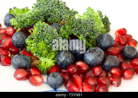 Vegetarische Rohkost. Salat von Brokkoli, Granatapfel Samen und Heidelbeeren eine Vielzahl von Nährstoffen. Extreme close-up mit selektiven Fokus. Stockfoto