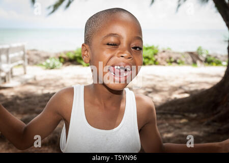 TURKS- UND CAICOSINSELN KARIBIK; vom 14. Juli 2012; Junge von Africican Ethnizität mit Mund mit fehlenden Zähnen und einem offenen Auge suchen glücklich. Stockfoto