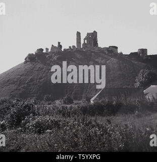 1940, historische, mit Blick auf die Ruinen von Corfe Castle, England, UK. Die Festung, die von William dem Eroberer erbaut, stammt aus dem 11. Jahrhundert und Befehle eine Lücke in der Purbeck Hills. Stockfoto