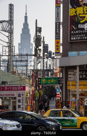 Die berühmten Uhrenturm oder NTT Docomo Yoyogi Gebäude erscheint mit der Straße Beiträge, die Stromleitungen inmitten einer belebten Straße Szene ausgerichtet Stockfoto