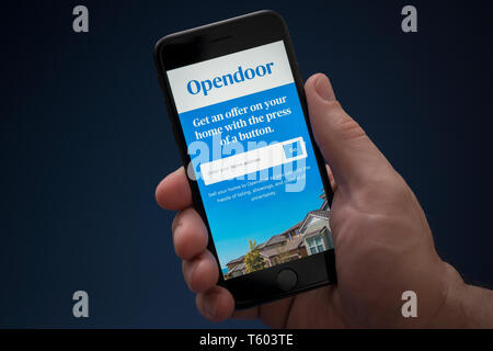 Ein Mann schaut auf seinem iPhone die zeigt die Opendoor Logo (nur redaktionelle Nutzung).