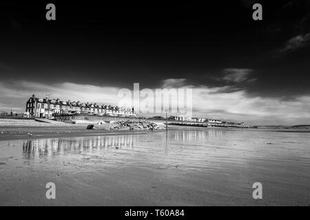 An der Küste bauten und viktorianischen Promenade spiegelt sich auf Auf nassem Sand. Tywyn in Mid Wales, Vereinigtes Königreich. Monochrome bearbeiten Stockfoto