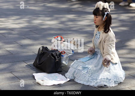 Asiatische Dame mit einem Teddybär auf dem Kopf in London betteln Stockfoto