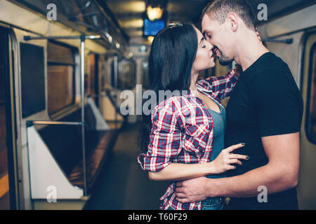 Junger Mann und Frau mit der U-Bahn. Paar in der U-Bahn. Leidenschaftlich küssen. Allein im Wagen. Ausschreibung Bild. Stand in der Mitte des U-Bahn carriag Stockfoto