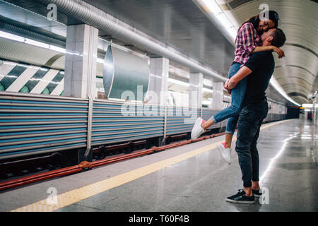 Junger Mann und Frau mit der U-Bahn. Paar in der U-Bahn. Fröhliches Bild der jungen Frau in die Hände. Sie lächeln. Glücklich zusammen. Liebe sotry. Undergroun Stockfoto