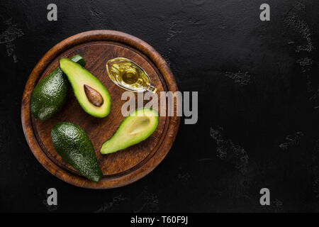 In Scheiben geschnitten und ganze Avocados und Öl an Bord Stockfoto