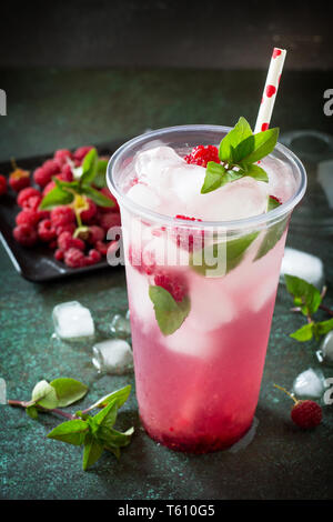 Erfrischende Sommer drink Zitrone, Minze, Eis und Himbeere mit Basilikum, Eis. Gläser mit kalten und gesundes Getränk auf einem dunklen Stein Hintergrund. Stockfoto