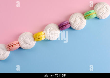 Süße bunte cookies Makronen oder MACARONS in einer Reihe auf farbenfrohen Pastelltönen Hintergrund. Kopieren Sie Platz. Köstliche französische Dessert Konzept. Stockfoto