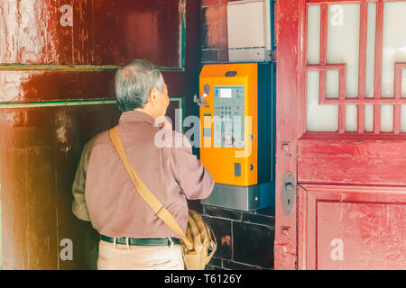 Alte taiwanesische Mann (alter Mann) mit einem Münztelefon seine Verwandten bei Longshan Tempel im Stadtteil Wanhua von Taipeh, Taiwan, Anruf Stockfoto