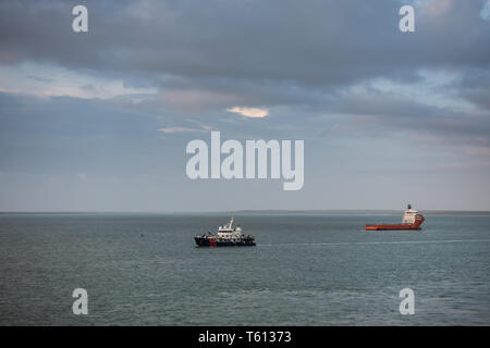 Darwin Australien - Februar 22, 2019: Zwei Schiffe fahren in die entgegengesetzte Richtung in den großen Hafen Bucht unter Abend cloudscape. Horizont ist eine kleine Zeile Stockfoto