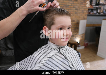 Ein kleiner Junge ist in hellen die Emotionen der Friseur auf seinem Gesicht getrimmt Stockfoto