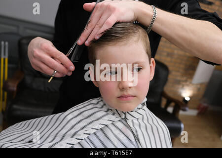 Ein kleiner Junge ist in hellen die Emotionen der Friseur auf seinem Gesicht getrimmt Stockfoto