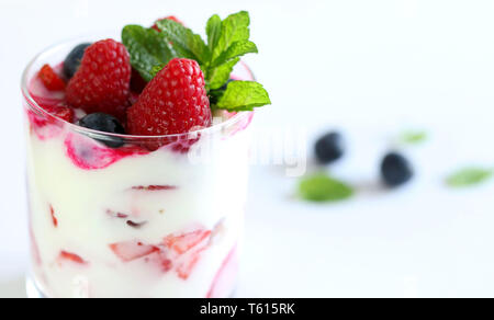 Dessert im Glas mit frischen Erdbeeren, Blaubeeren, Himbeeren und Joghurt, auf weißem Hintergrund Stockfoto