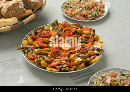 Traditionelle marokkanische Gerichte mit Sardinen und Gemüse, Salat und ein Korb mit Brot Stockfoto