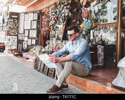 Stattlicher Mann mit einem Touristische Karte erkunden Sie die Sehenswürdigkeiten der schönen Stadt Muscat. Close-up. Konzept der Freizeit und Reisen Stockfoto