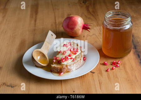 Brot, Käse, Honig und Granatapfel auf rustikalen Holztisch - Food still life Stockfoto