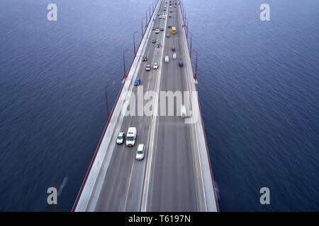 Schöne Brücke über Fluss Dnepr mit roten Straßenlaternen und Fechten in der Stadt der Dnjepr in der Ukraine. Es ist ein unscharfer Verkehr auf Sie. Antenne horiz. Stockfoto
