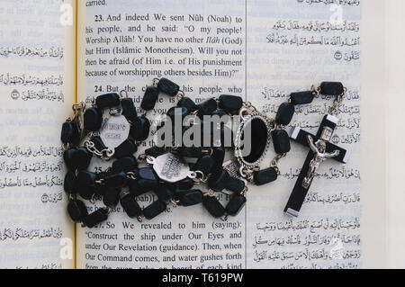 Katholischen Rosenkranz sitting on Top of eine offene Qu'ran. Stockfoto