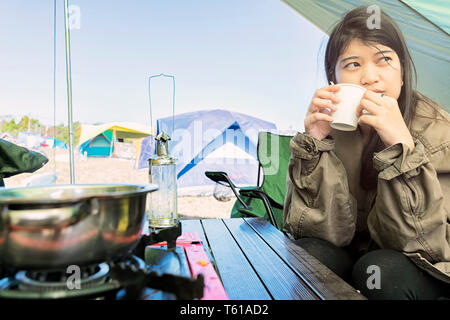 Bild der Frau in den Stühlen außerhalb des Zeltes saß. Paar camping im Wald. Camping Zelt unter den Pinienwald in der Nähe des Sees mit schönen sunli Stockfoto