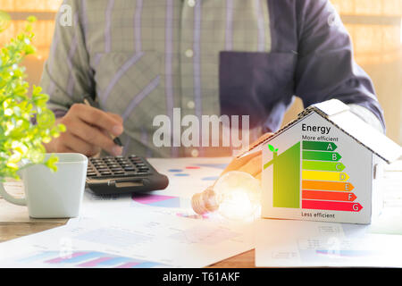 Männer, die Berechnung von Einsparungen von Energie. Hand mit einem Stift. Detail Haus Wirkungsgrad auf digitalen tablet Bildschirm. Konzept der Ecologica Stockfoto