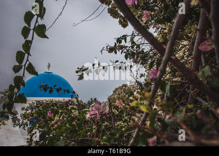 Detail der blauen Kuppel und Bougainvillea im Ort Oia auf eine seltene regnerischen Tag, Santorini, Griechenland Stockfoto