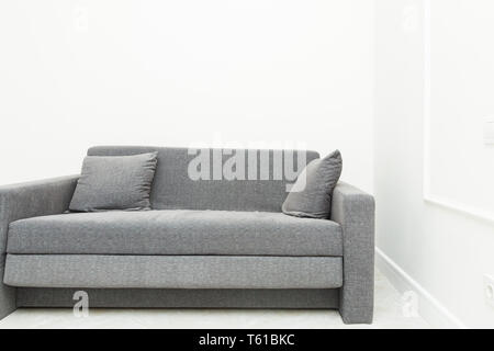 Klassische Moderne graue Sofa mit Kissen in den hellen Räumen der Wohnung Stockfoto