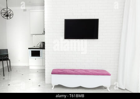 Apartment Interieur in hellen, modernen Stil. TV an der Wand und eine Bank mit einem farbigen Akzent. Stockfoto
