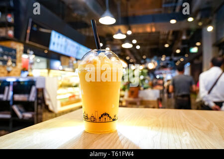 Mango fruchtig Frappe, Smoothies und Shakes in Kunststoff Nehmen Schale auf dem Holztisch in Getränkehändler. Stockfoto