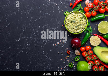 Traditionelle mexikanische Lateinamerikanischen Soße Guacamole und Zutaten auf schwarzen Steintisch. Ansicht von oben mit der Kopie. Stockfoto