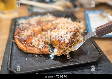 Okonomiyaki; tranditional Japanisches Essen Stil handgefertigt und auf einer Eisenplatte Schnitt bereit zu dienen und in einem Restaurant essen. aus nächster Nähe erschossen. Stockfoto