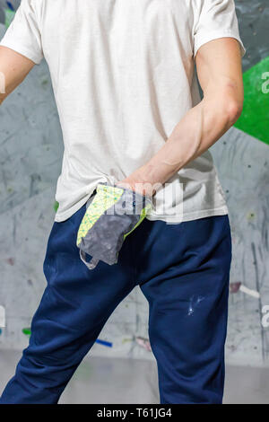 Kletterer Mann schob seine Hände in eine Tasche von Magnesia Pulver hinter seinem Rücken in der Boulder Halle Stockfoto