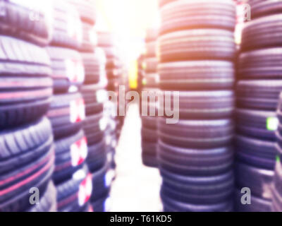 Abstrakte verschwommenen Hintergrund mit Autoreifen zum Verkauf. Blur Foto von vielen PKW-Reifen im Shop zum Verkauf. Auto Parts Store bokeh backgtound. Weiche ligh Stockfoto