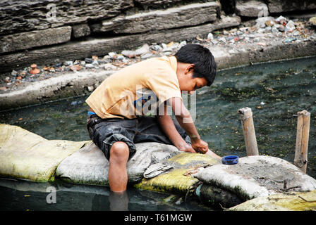 Kid sammelt Münzen in der bagmati Fluss, Kathmandu, Nepal. In Nepal, 25,2 % der Bevölkerung lebt unterhalb der nationalen Armutsgrenze im Jahr 2010 Stockfoto