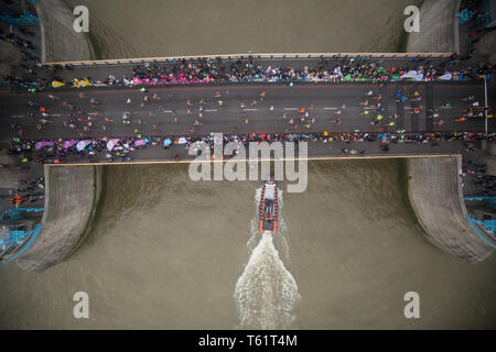Ein Boot Kreuze unter Tower Bridge als Läufer an den 2019 Virgin Money London Marathon. Stockfoto