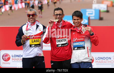 Marokko El Amin Chentouf (Mitte) feiert den Gewinn der WPA Marathon neben dem Zweitplatzierten Spanien Alberto Suarez Laso (links) und vierten platziert Japans Tadashi Horikoshi (rechts) während der 2019 Virgin Money London Marathon. Stockfoto